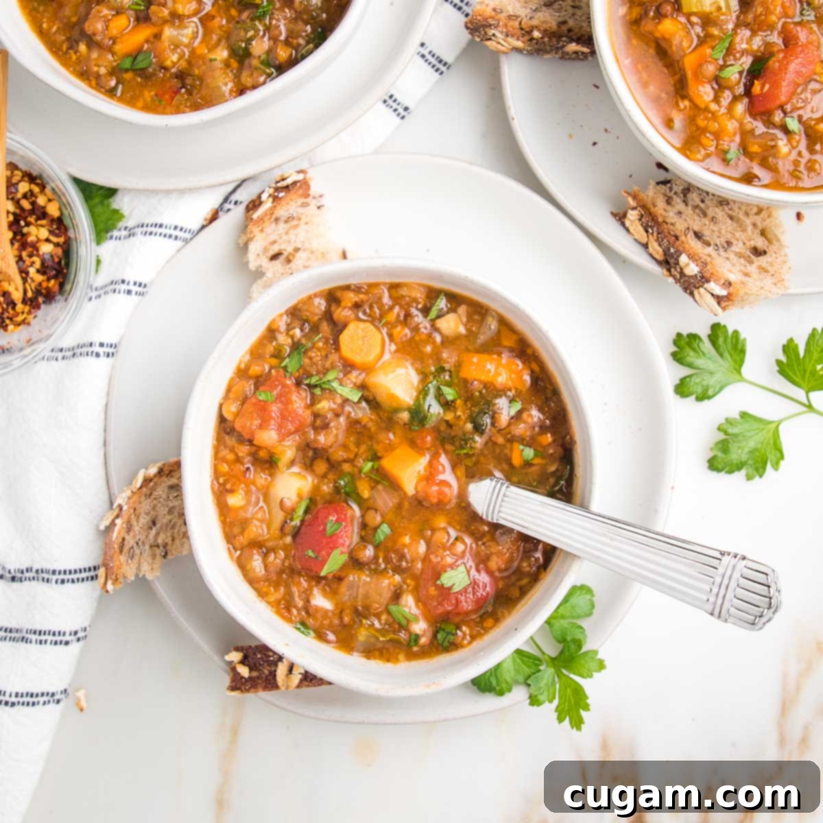 Chunky vegetable lentil soup in bowls with crusty bread pieces on the side, highlighting its rich texture and nourishing appeal.