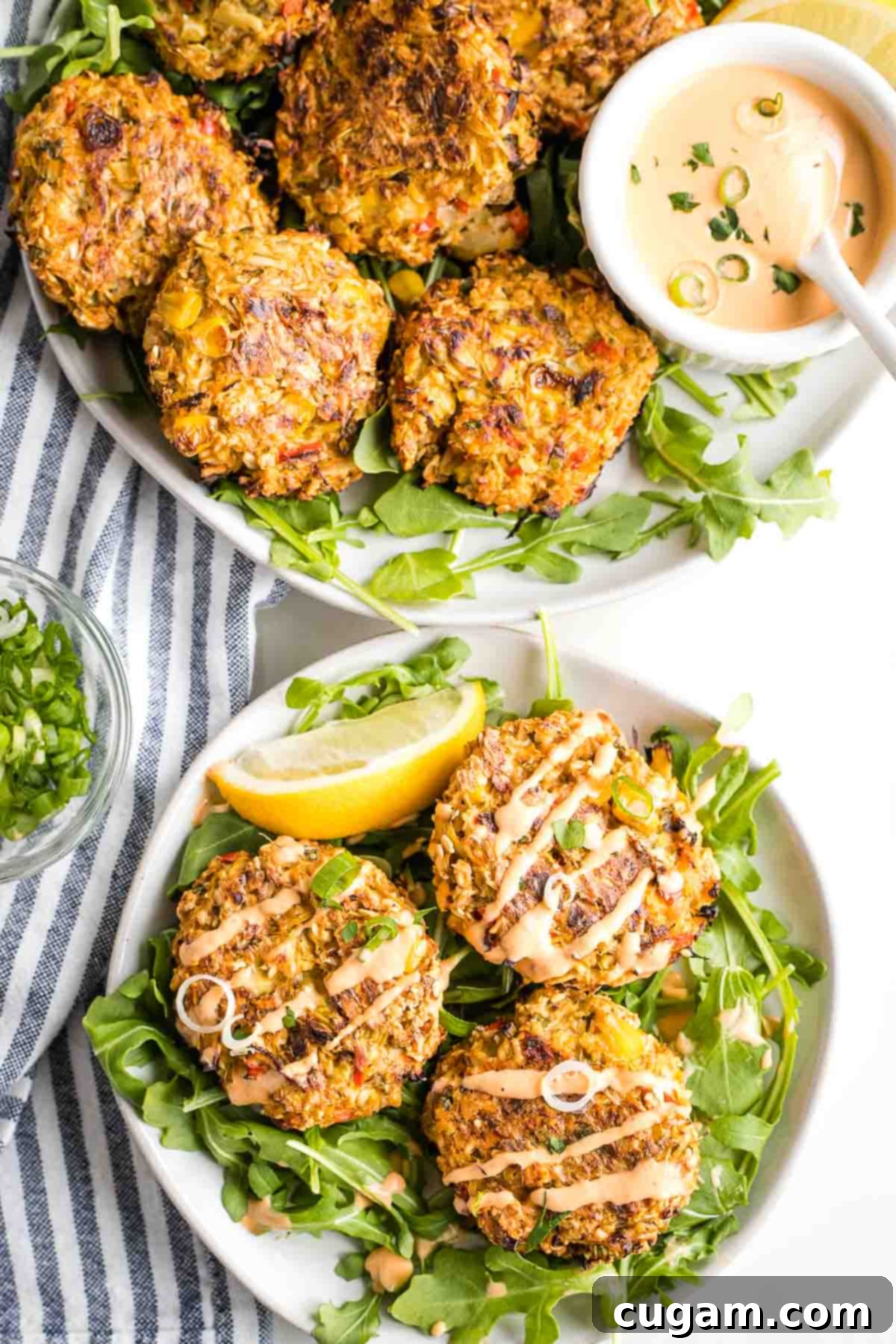 Vegan crab cakes on a platter with sriracha dipping sauce, plus a small plate with arugula and crab cakes. 