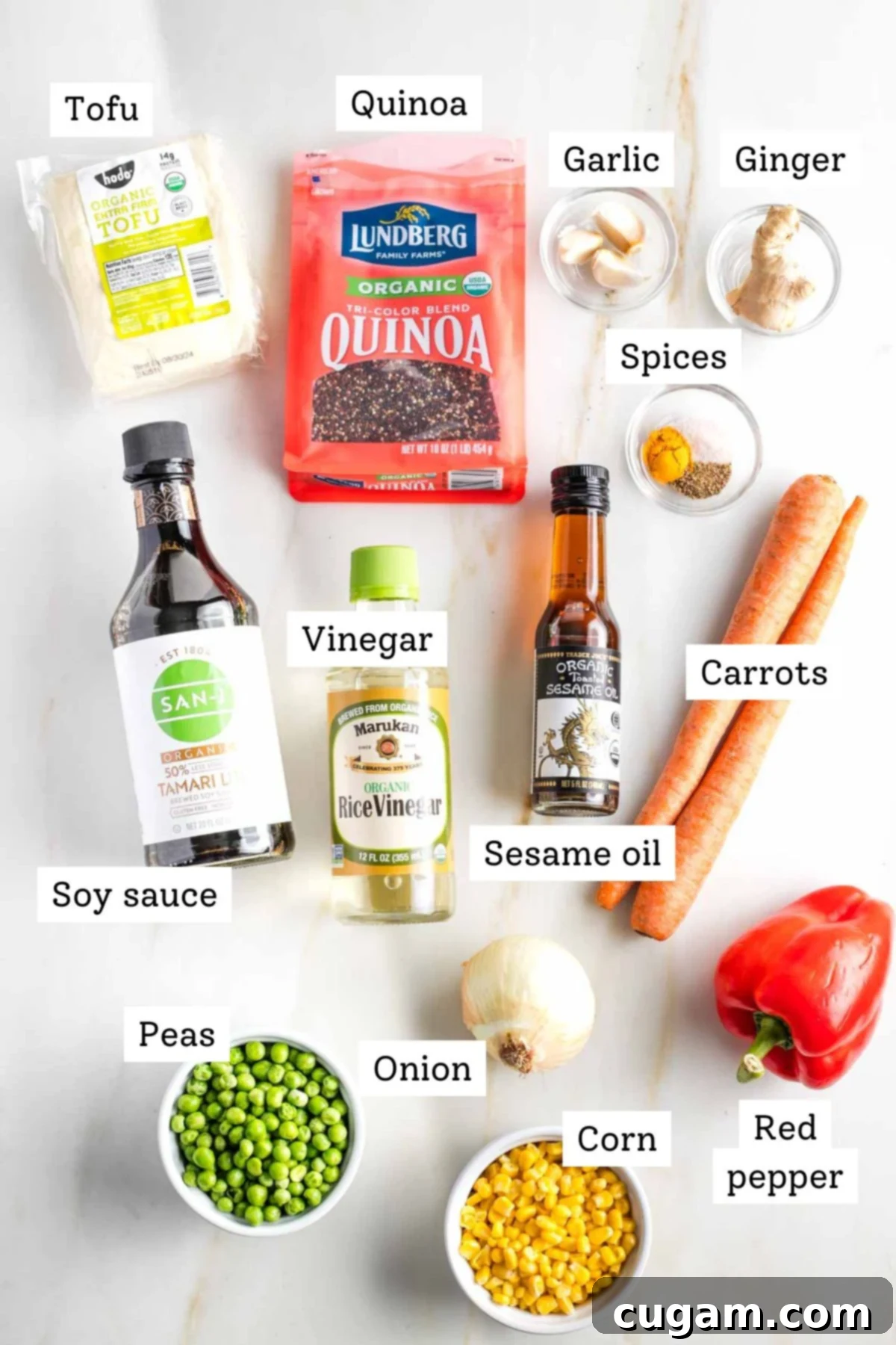 Plant-Powered Tofu Quinoa Stir-Fry 4 Labeled ingredients for vegan quinoa fried rice: cooked quinoa, extra-firm tofu, tamari, rice wine vinegar, toasted sesame oil, diced carrots, red bell peppers, frozen peas, frozen corn, onions, turmeric, salt, pepper, minced garlic, and grated ginger.