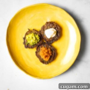 Three latkes with different toppings: applesauce, guacamole and sour cream.