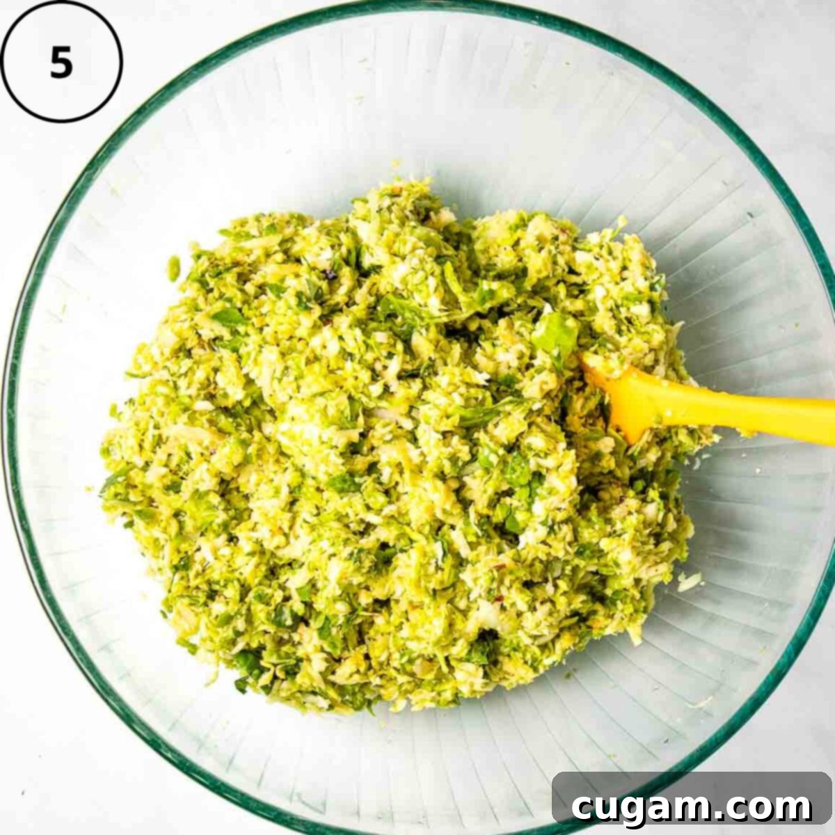 Brussels sprouts latke mixture in a glass bowl.
