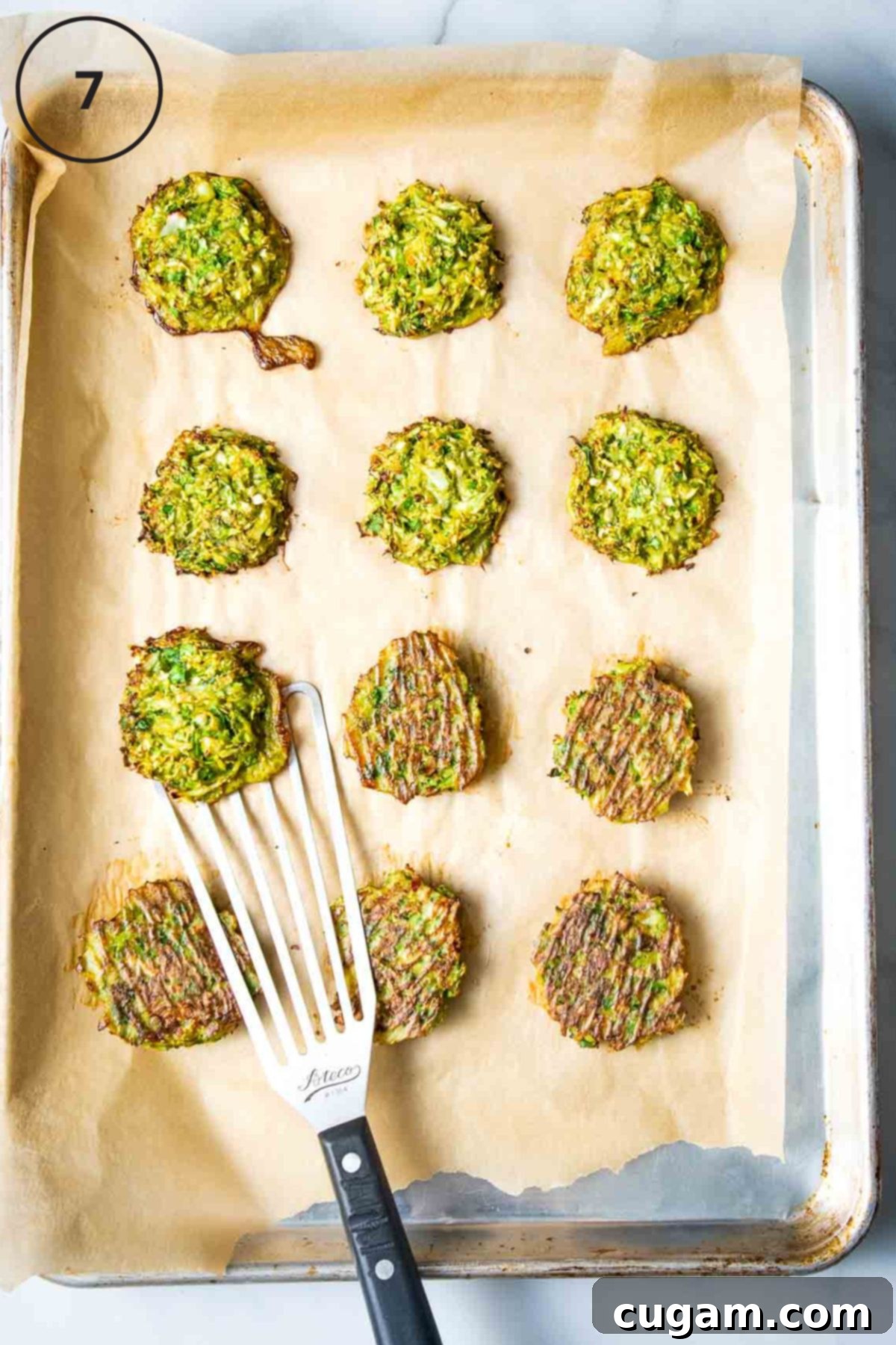 Flipping brussels sprouts latkes over on a tray lined with parchment.