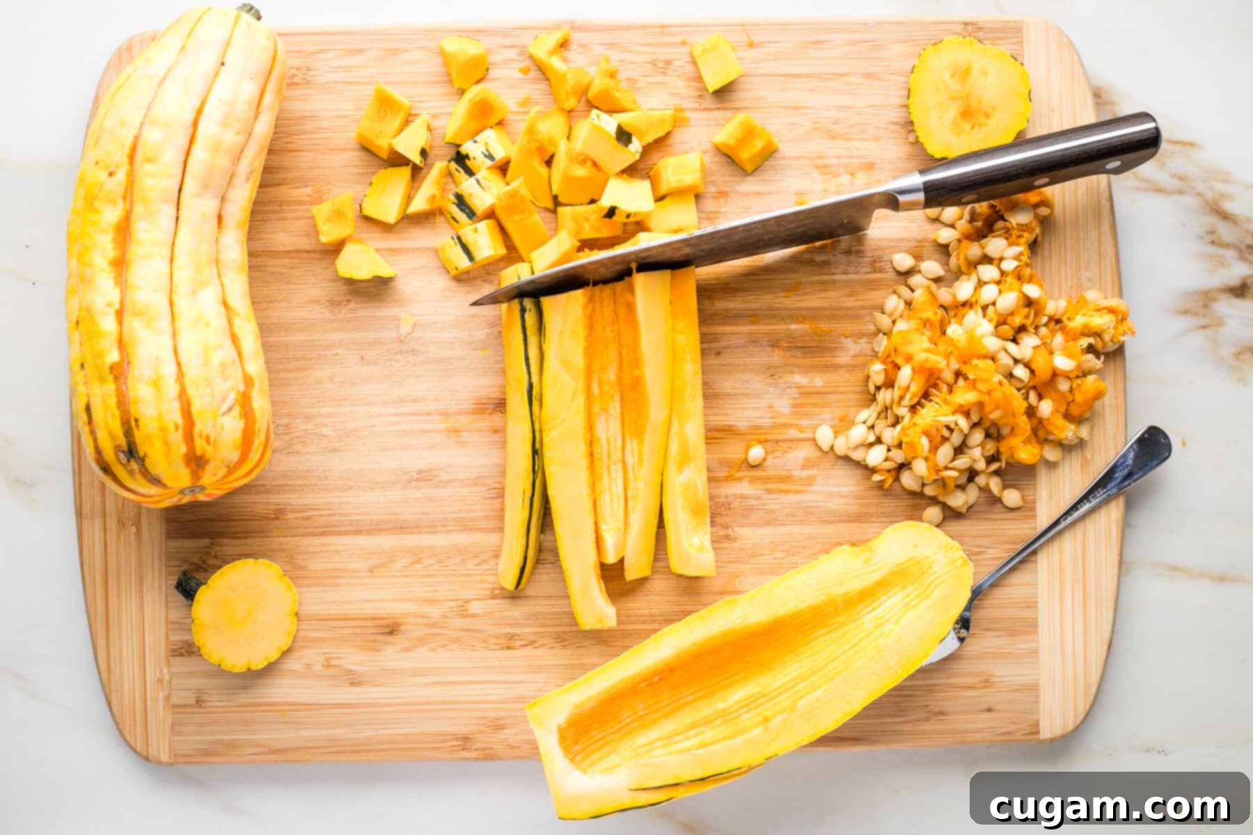Delicata squash cut in half lengthwise, seeds scooped out and showing how to cut long and then across for small dice.