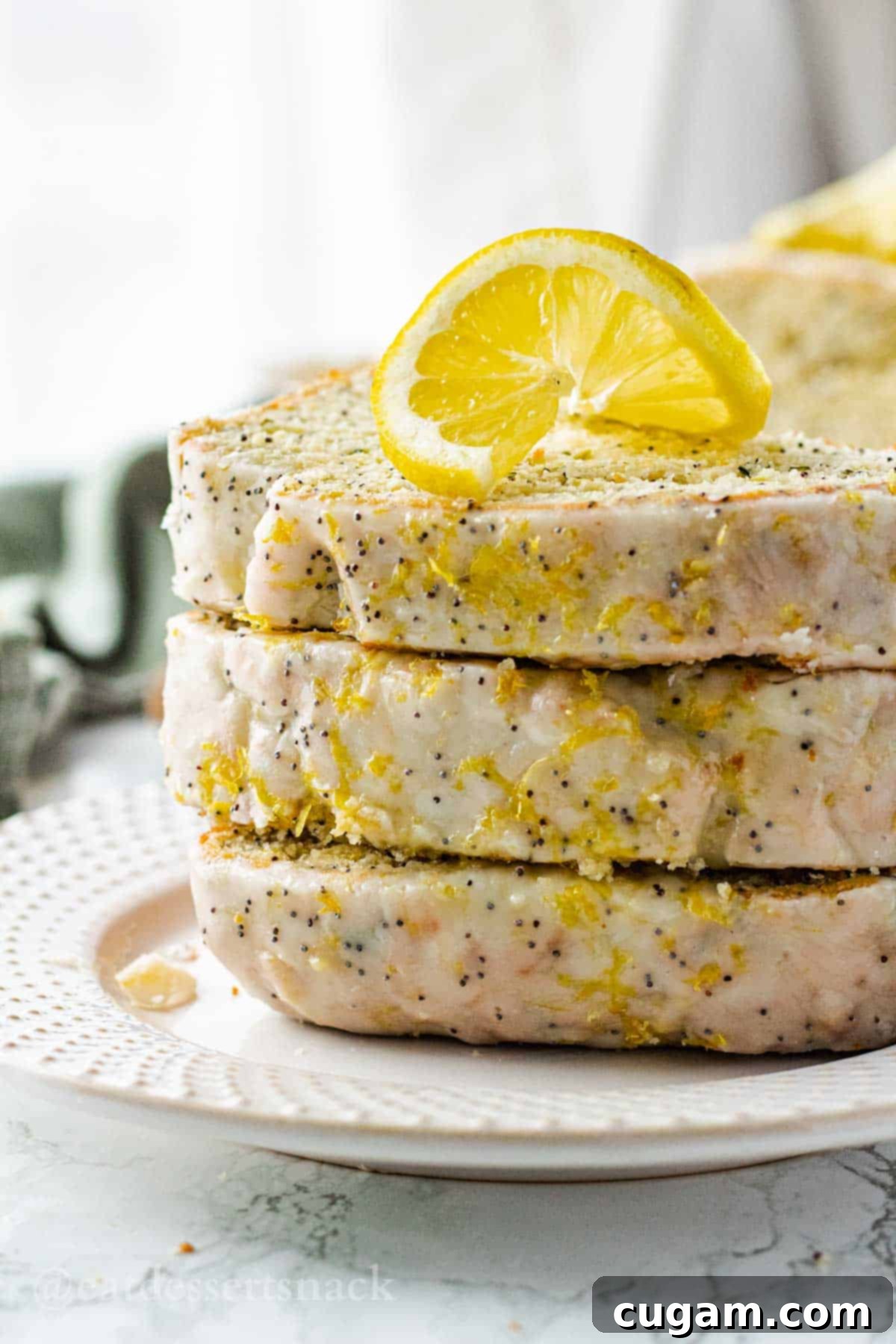 3 slices of lemon zucchini bread on white plate with lemon slice.