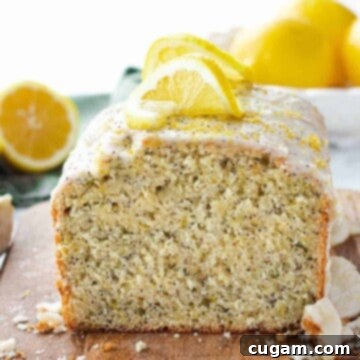 Baked lemon zucchini poppyseed loaf sliced on a wood cutting board.