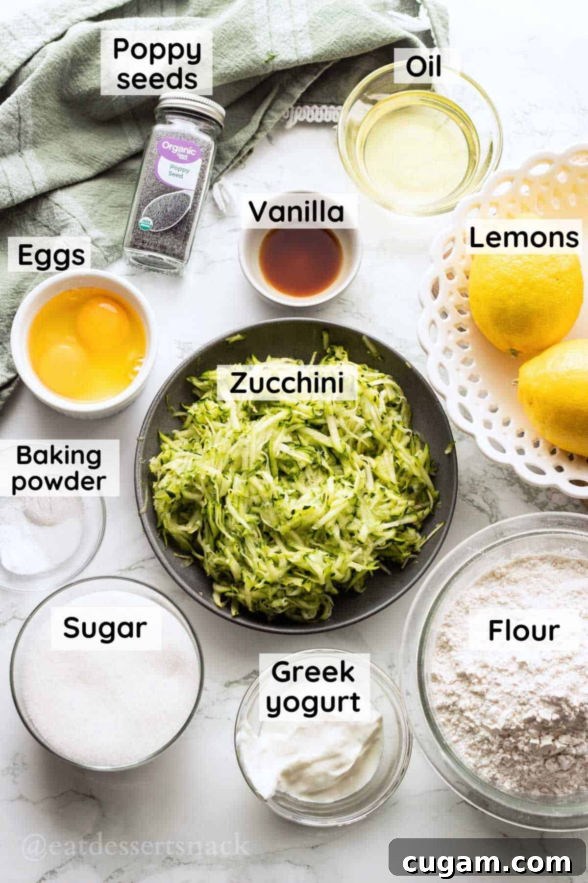 Lemons, flour, greek yogurt, white sugar, baking powder, salt, eggs, vanilla, poppyseeds, oil, and grated zucchini in bowls on marble countertop.