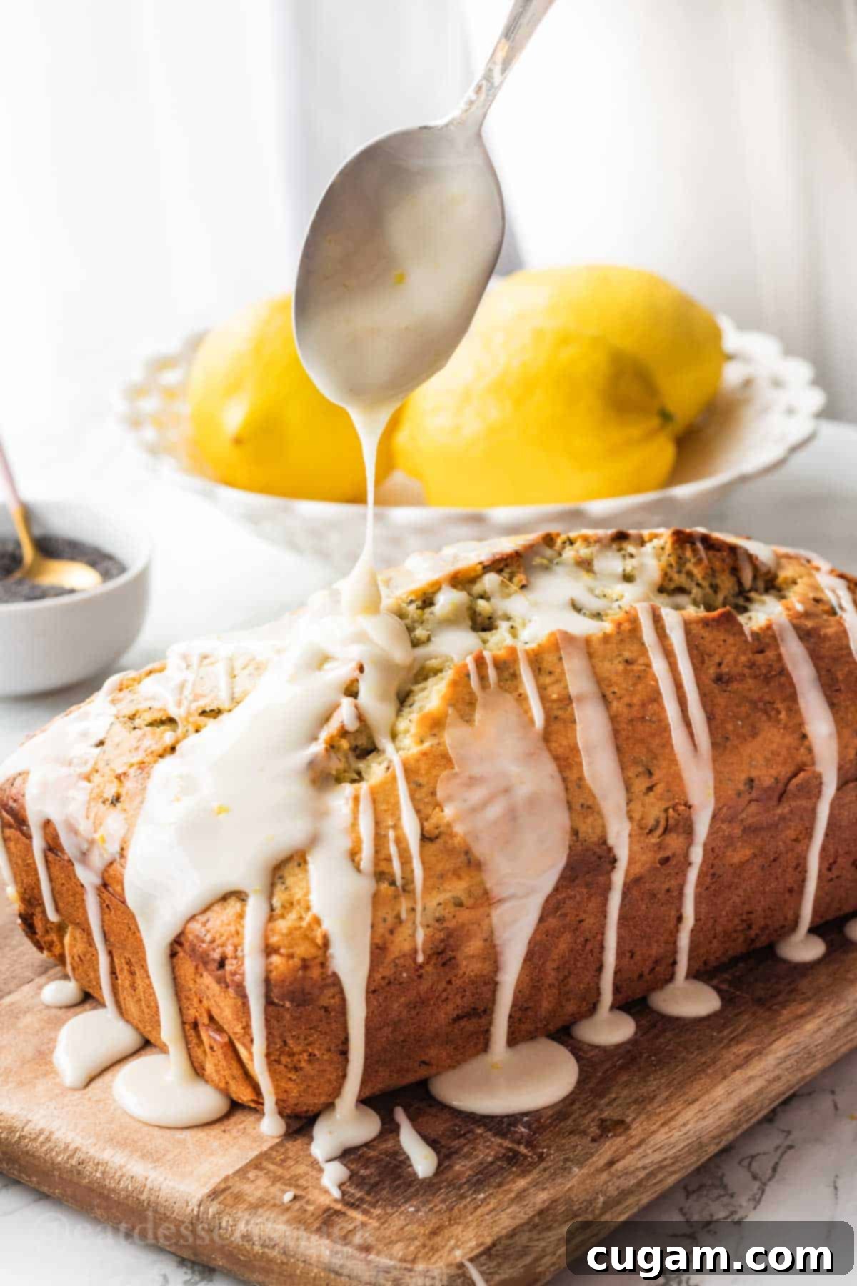 Spoon drizzling lemon icing onto baked loaf of lemon zucchini bread.