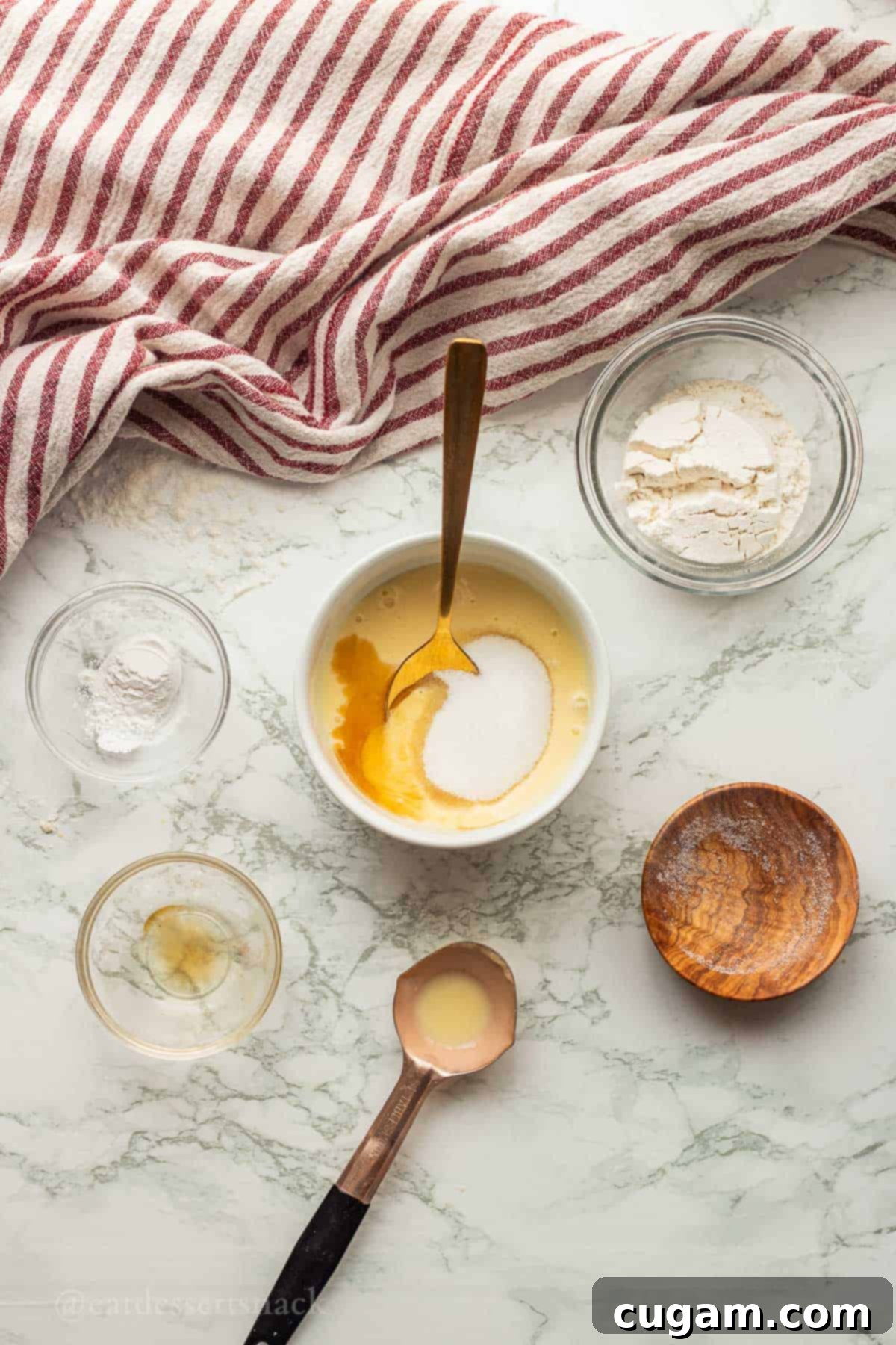 Eggnog, vanilla, and sugar in white bowl with spoon, ready to be mixed.