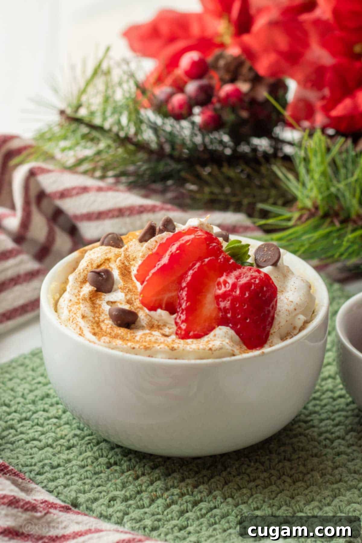 Eggnog mug cake topped with fresh strawberries and chocolate chips, ready to be enjoyed.