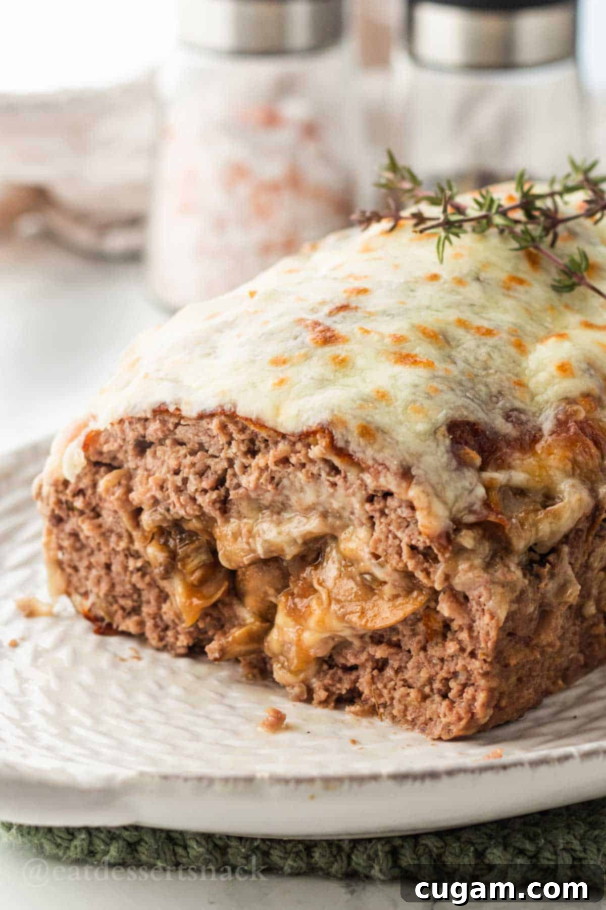 Baked mushroom meatloaf on white platter, garnished with fresh herbs.