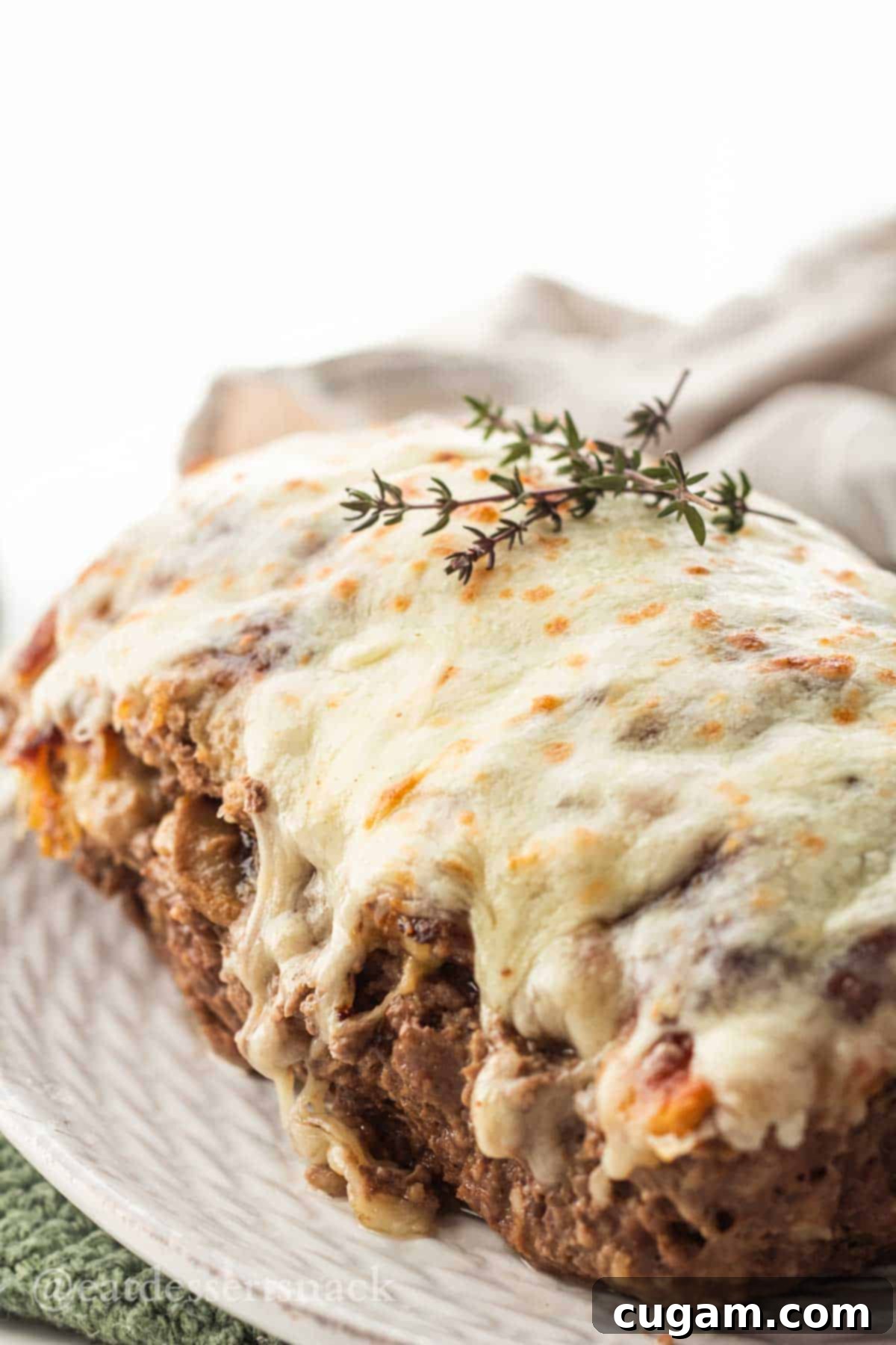 Baked mushroom meatloaf on white platter with thyme on top.