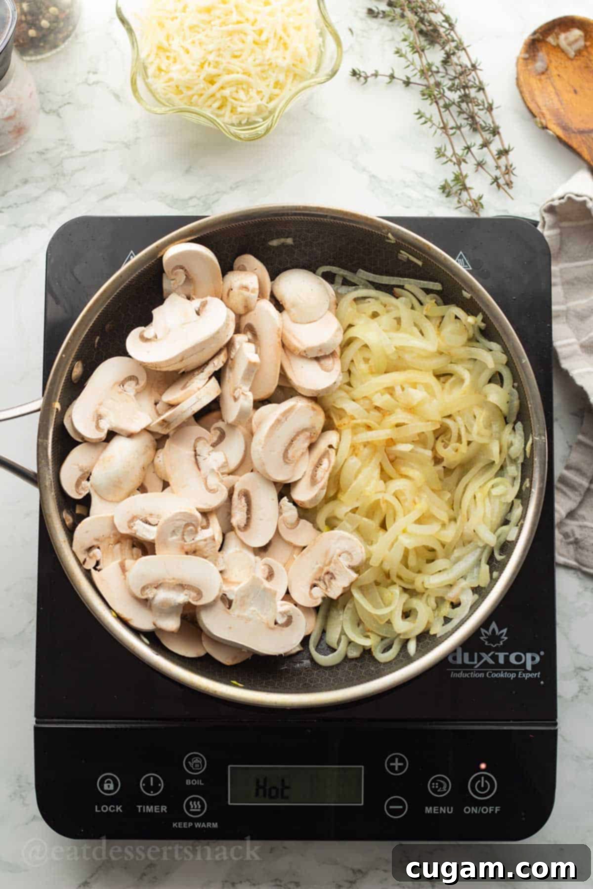 Raw mushrooms in metal pan with partially cooked onions.