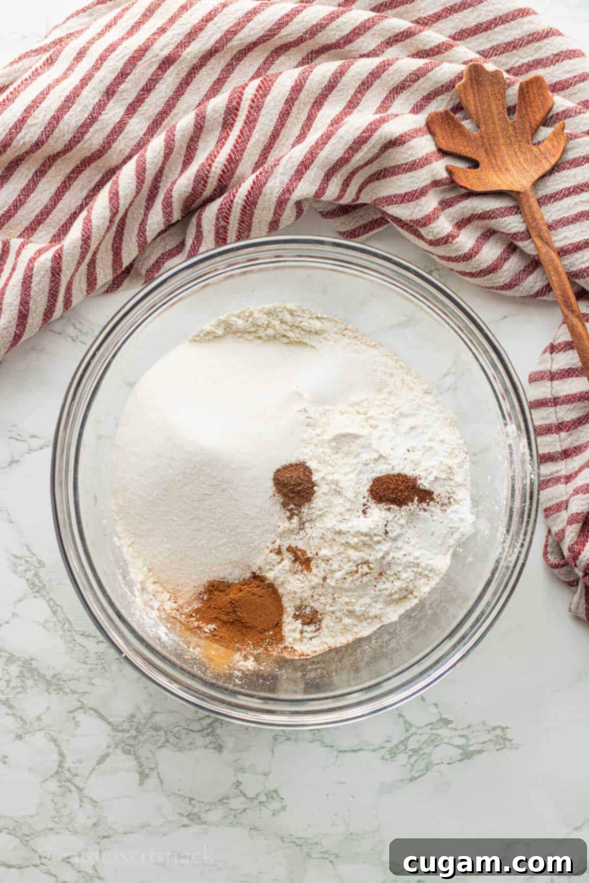 Dry ingredients for caramel apple cinnamon scones in a clear glass mixing bowl, perfectly combined.