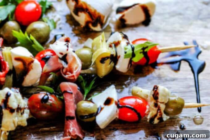 Colorful Italian Antipasto Skewers featuring cured meats, cheese, olives, and tomatoes, drizzled with balsamic glaze.