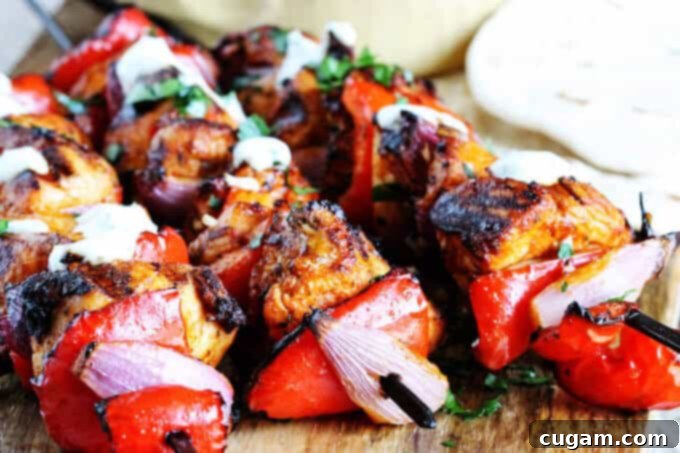 A delicious grilled Mediterranean Chicken Kebab on a plate, garnished with fresh dill and a lemon wedge, alongside a bowl of creamy garlic yogurt sauce.