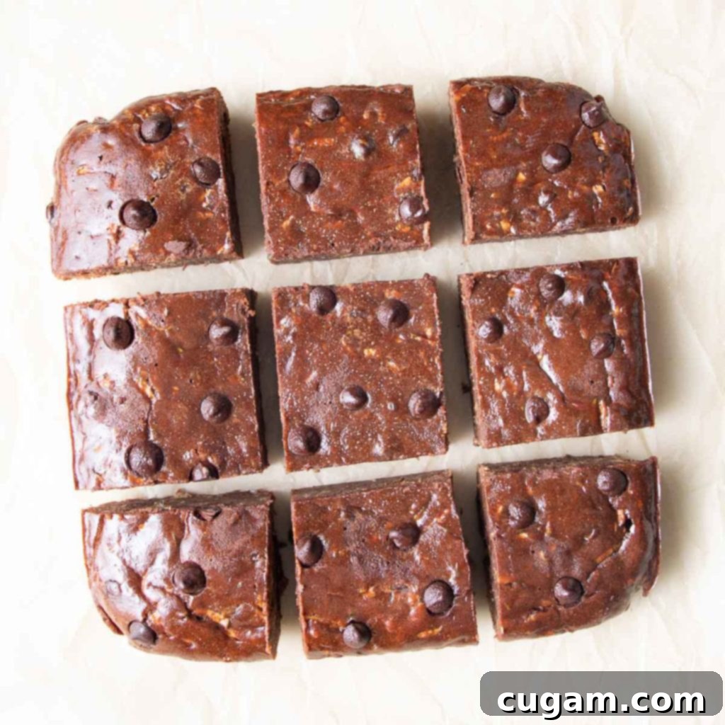 Close-up of freshly baked chocolate zucchini brownies cut into neat squares, showcasing their moist texture and dark chocolate chips.