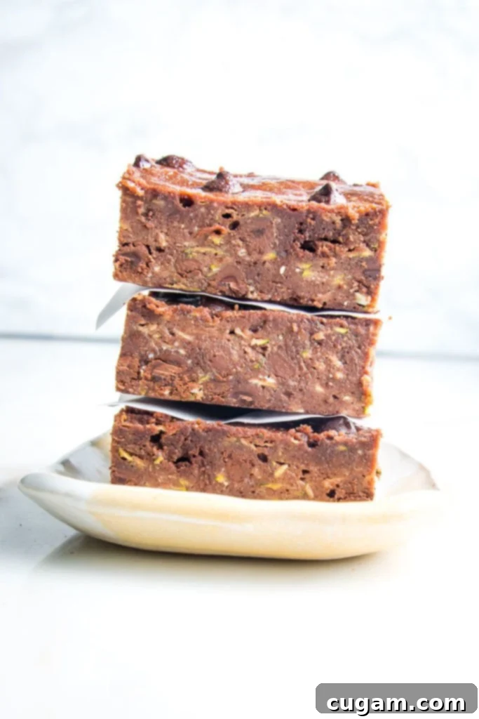 A stack of freshly baked chocolate zucchini brownies, sprinkled with extra chocolate chips for a tempting visual.