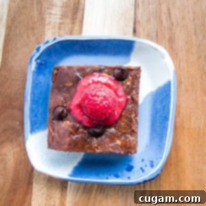 brownie on a bright blue plate with raspberry sauce on top.