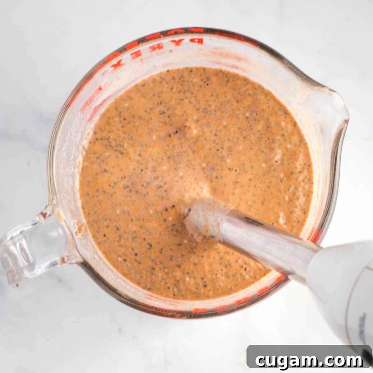 Mixing chia seeds into chocolate milk with an immersion blender. 