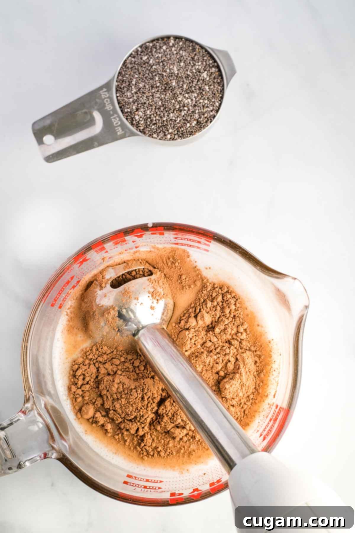 Immersion blender combining almond milk with cocoa powder. 