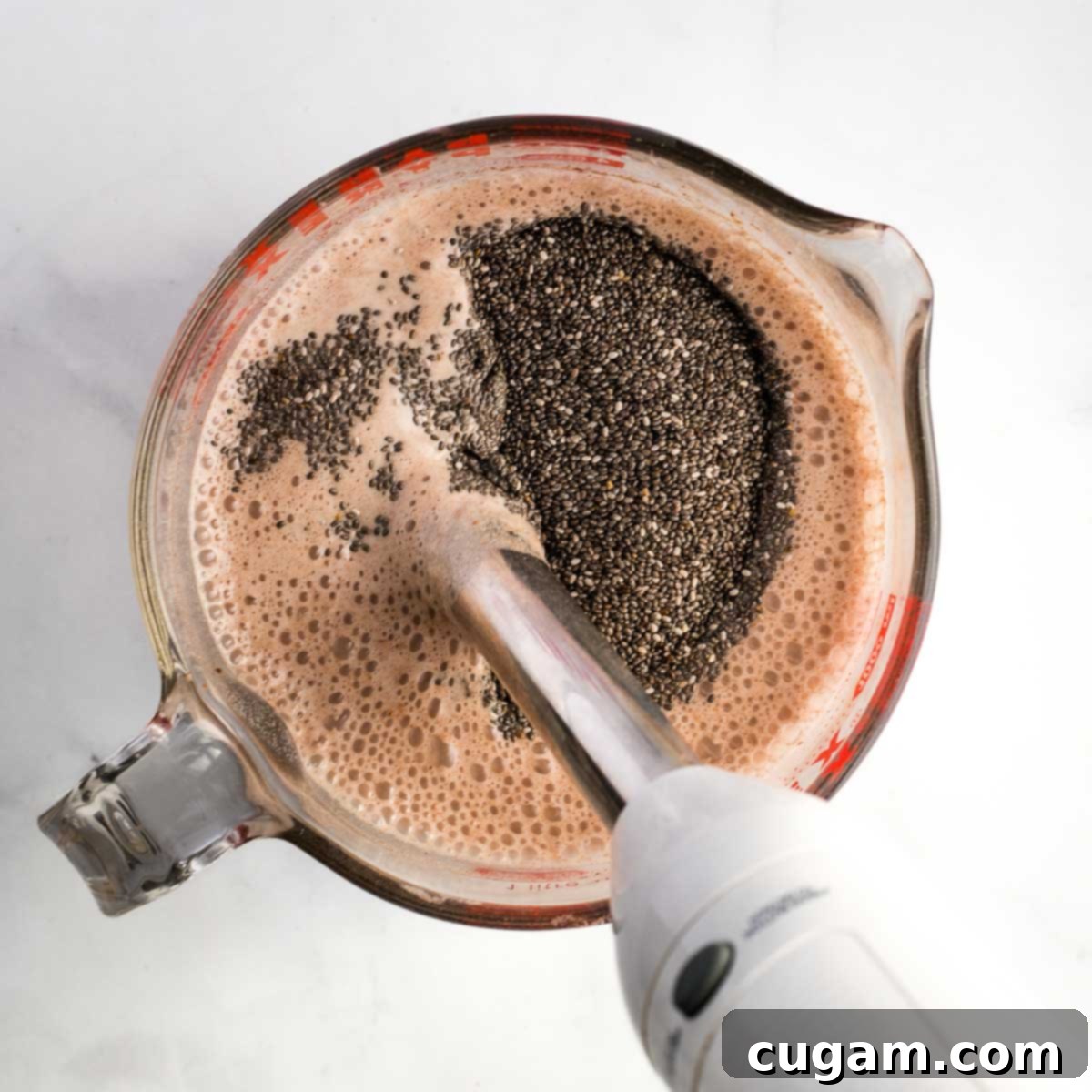 Mixing chia seeds into chocolate pudding with an immersion blender. 