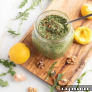 Vegan Arugula Walnut Pesto 10 Jar of pesto sprinkled with crushed red pepper, plus lemons, walnuts, arugula and garlic.