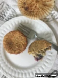 White plate showcasing a delicious blueberry muffin cut open, highlighting its moist and tender texture. A perfect gluten-free treat.