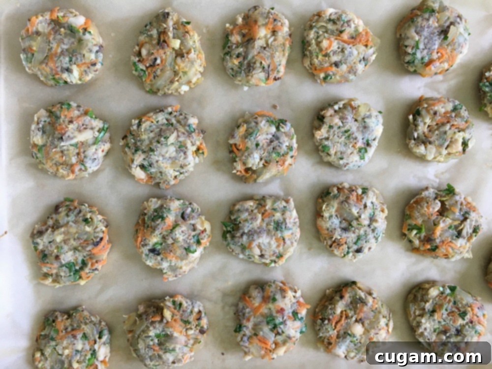 A baking tray filled with mini white bean burgers, ready to bake to become appetizer burger sliders.