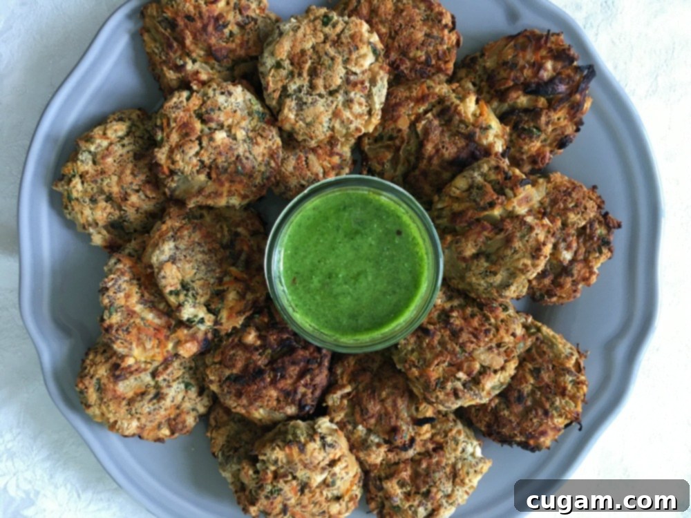A round plate filled with mini veggie burgers with a small glass dish of bright green dipping sauce in the middle.