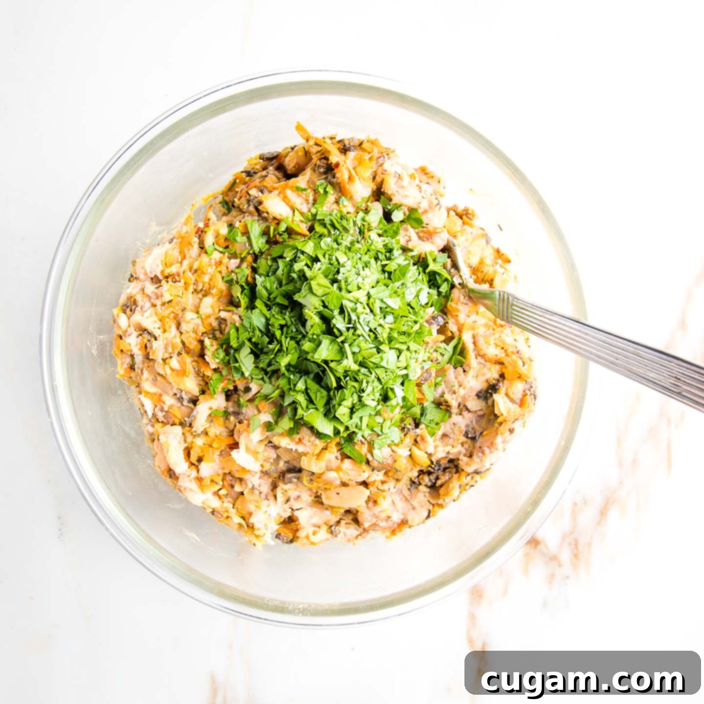Bowl of mashed white beans plus veggies with fresh parsley on top.