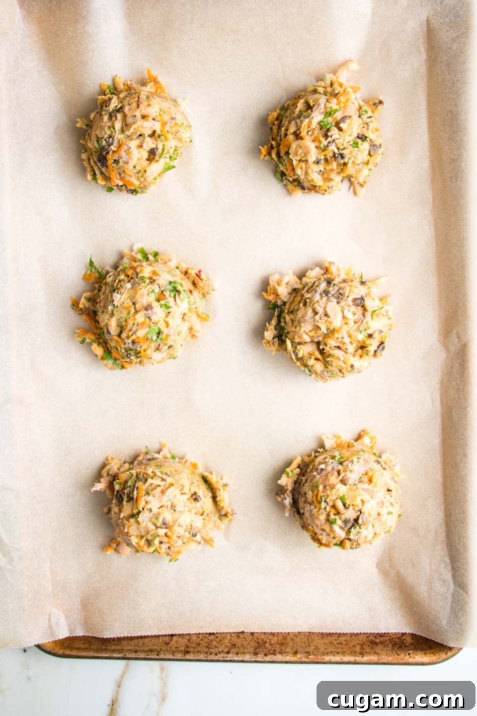 Large scoops of bean burger batter on a lined baking tray.