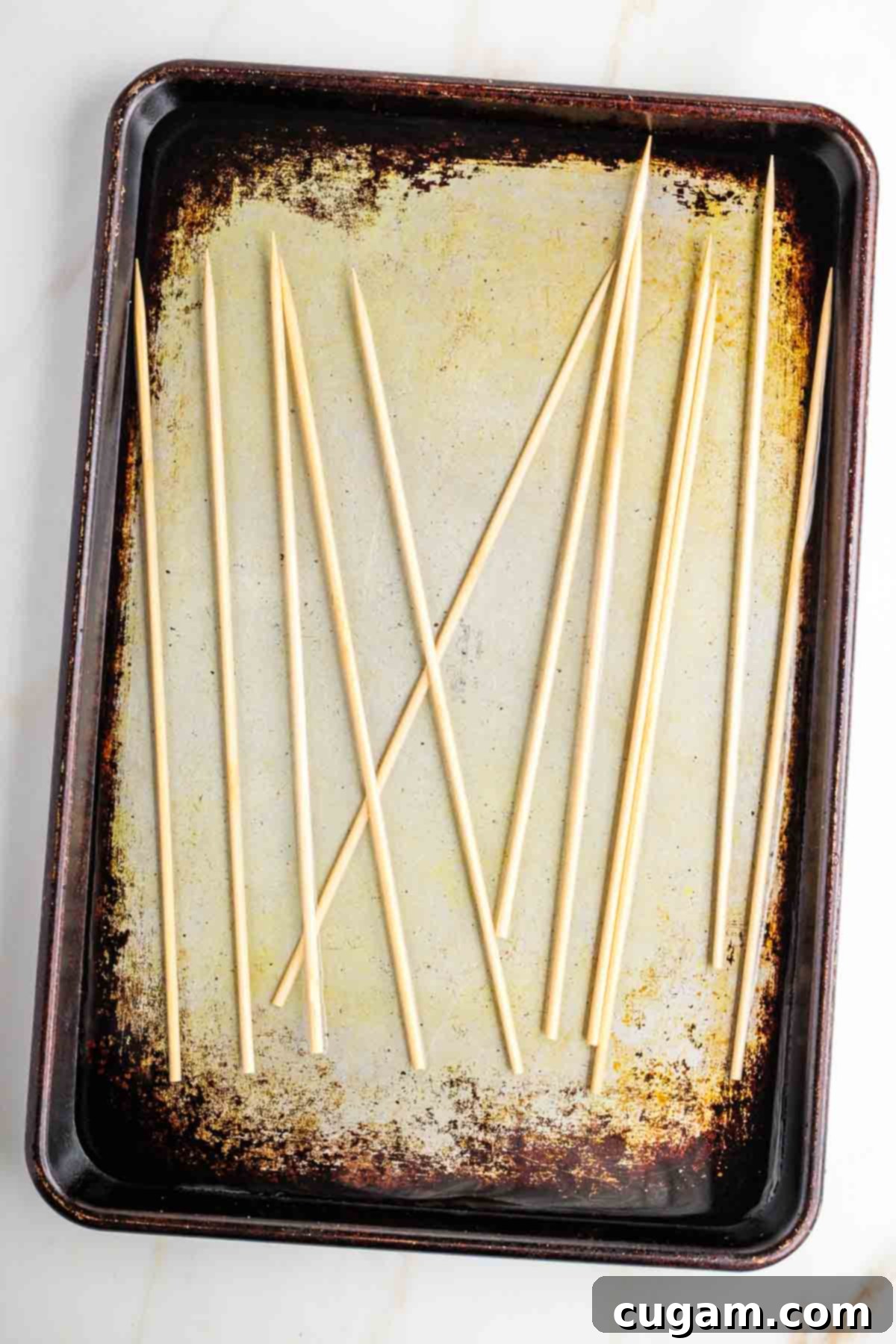 Mediterranean Harvest Skewers 7 Bamboo skewers soaking in water on a rimmed baking sheet.