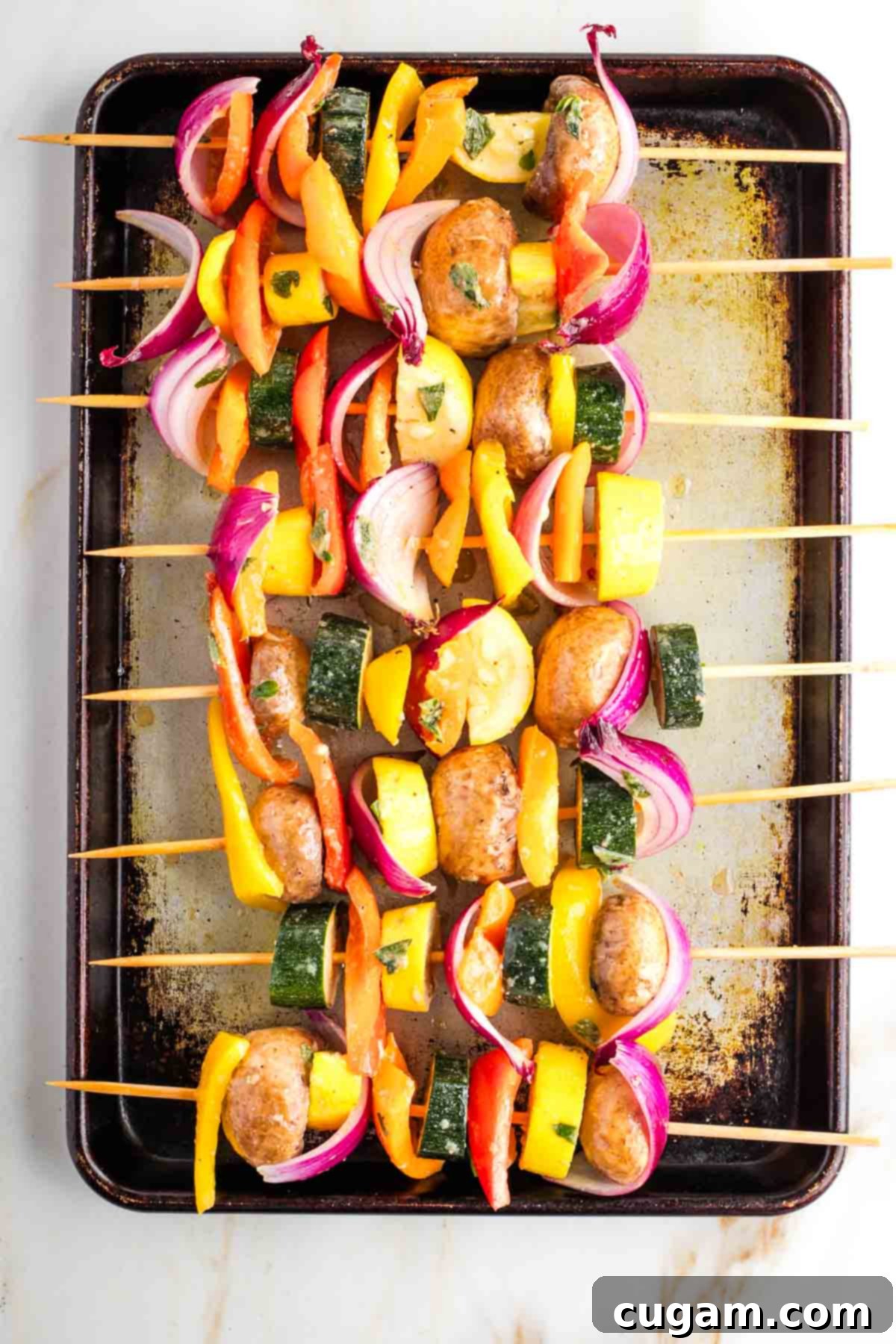 Mediterranean Harvest Skewers 8 Colorful vegetable chunks on bamboo skewers stilling on a rimmed baking sheet.