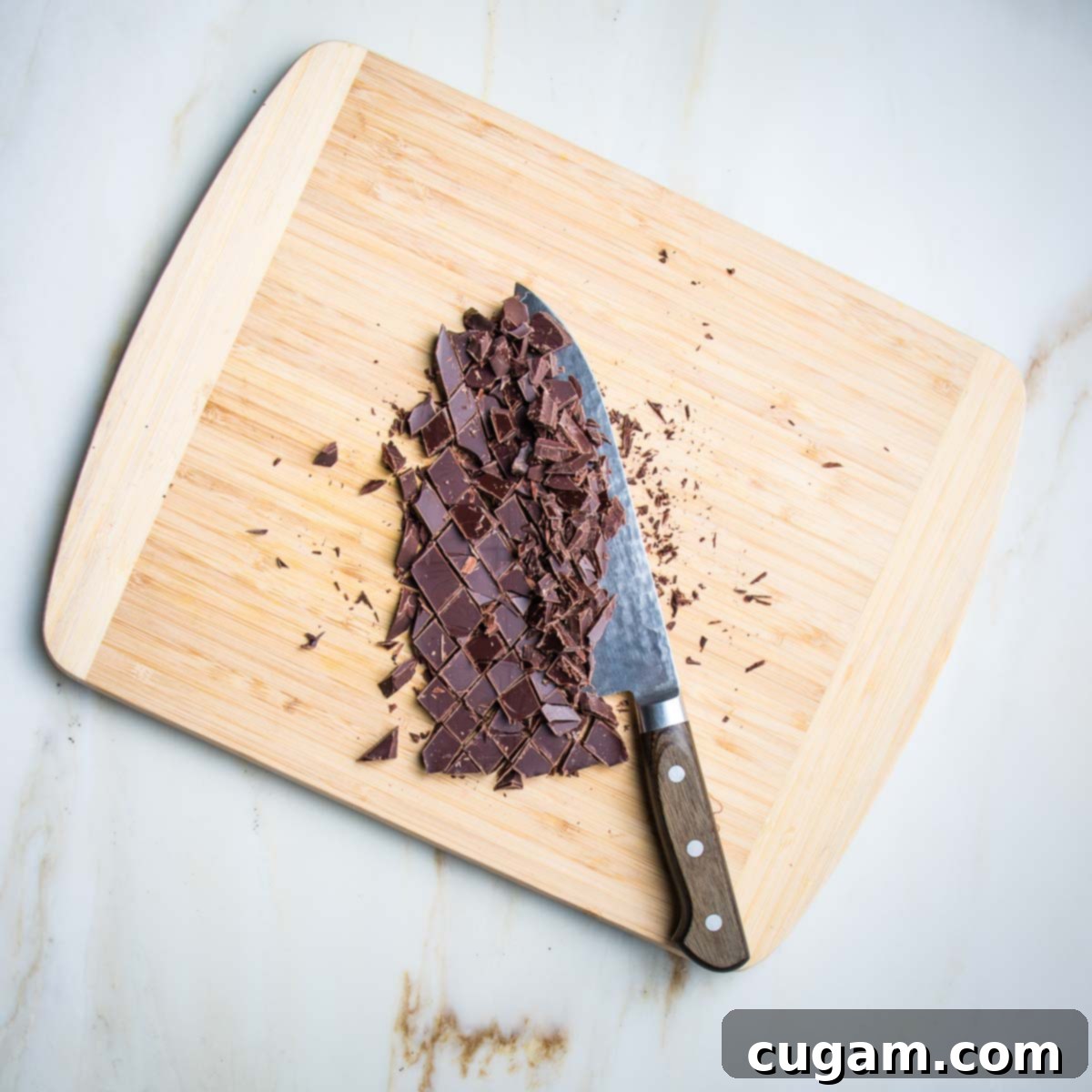 Delicious Vegan Gluten-Free Chocolate Chunk Skillet Cookie 7 High-quality dark chocolate bar chopped into irregular chunks on a wooden cutting board.