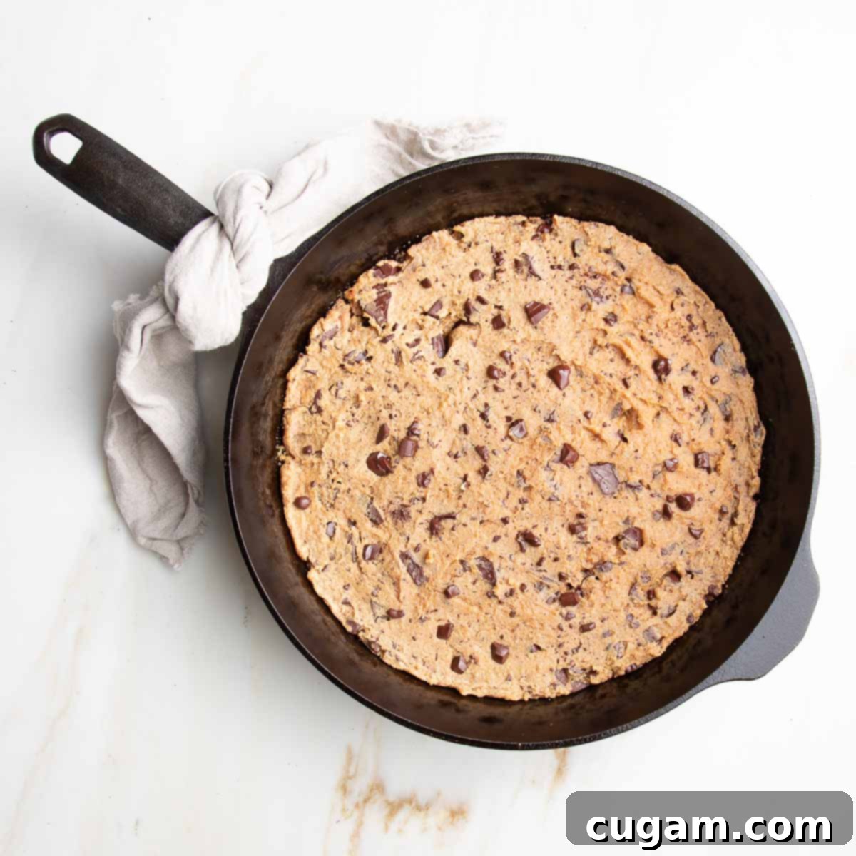 Delicious Vegan Gluten-Free Chocolate Chunk Skillet Cookie 10 Baked chocolate chunk cookie in a cast iron skillet, golden brown on the edges with a slightly soft center.