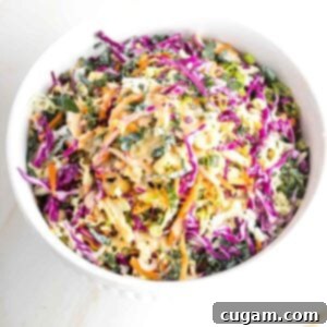 Large bowl with colorful cabbage, carrots, kale and a creamy dressing.