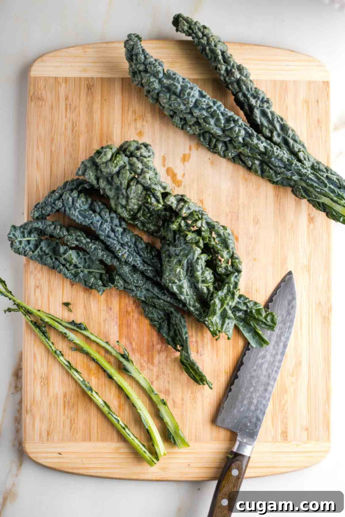 Lacinato kale, with stems removed, on a wooden board.