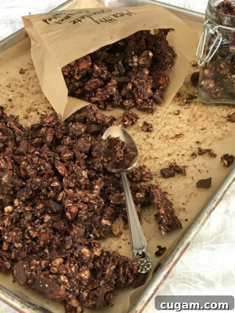 Chocolate granola being spooned into a small paper bag. 