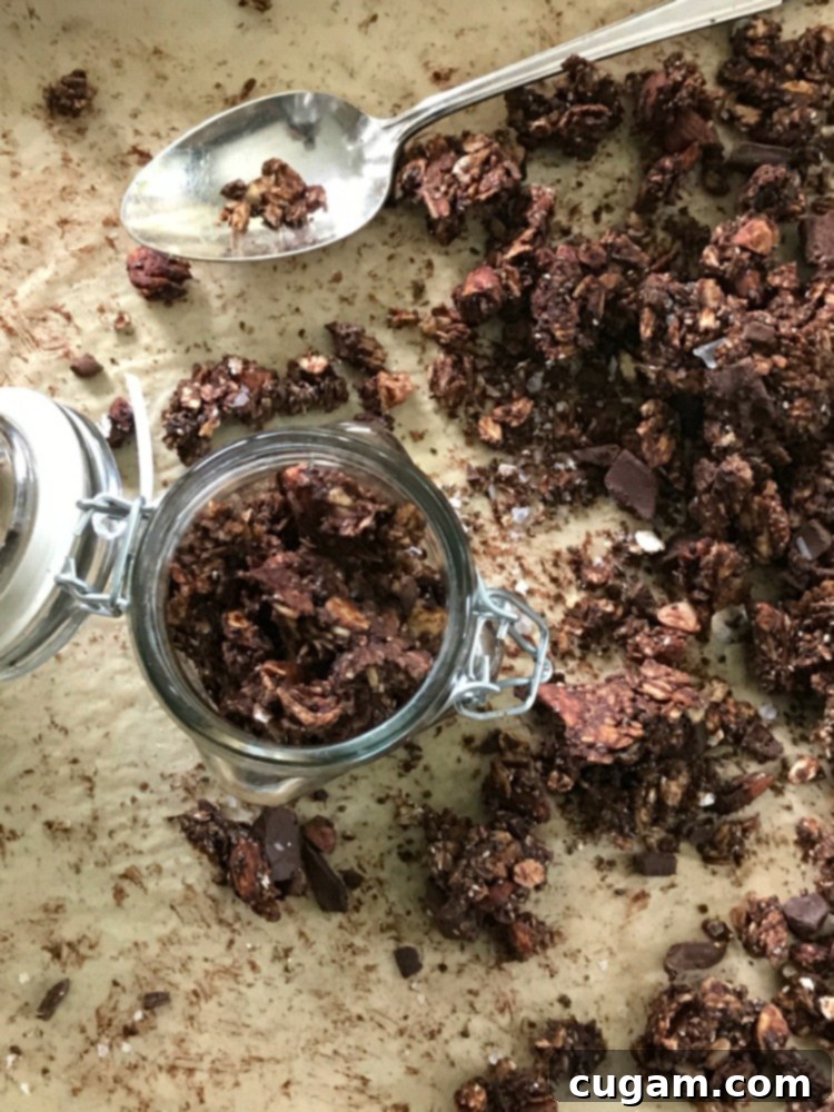Jar filled with chocolate granola straight from a baking pan. 