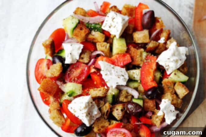 Greek Panzanella Salad combines traditional Greek salad flavors, like Kalamata olives, and tangy feta with bread cubes toasted in tasty garlicky vinaigrette.
