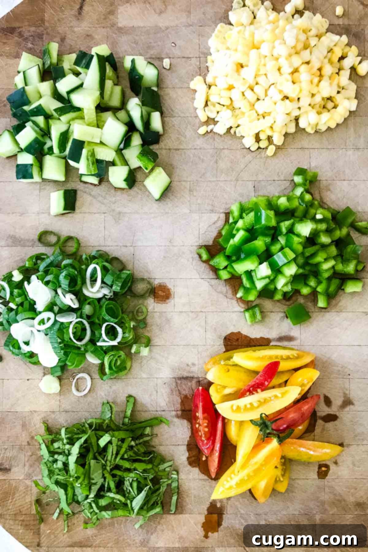 Piles of neatly chopped vegetables including tomatoes, cucumbers, bell peppers, scallions, and corn kernels, ready for gazpacho.
