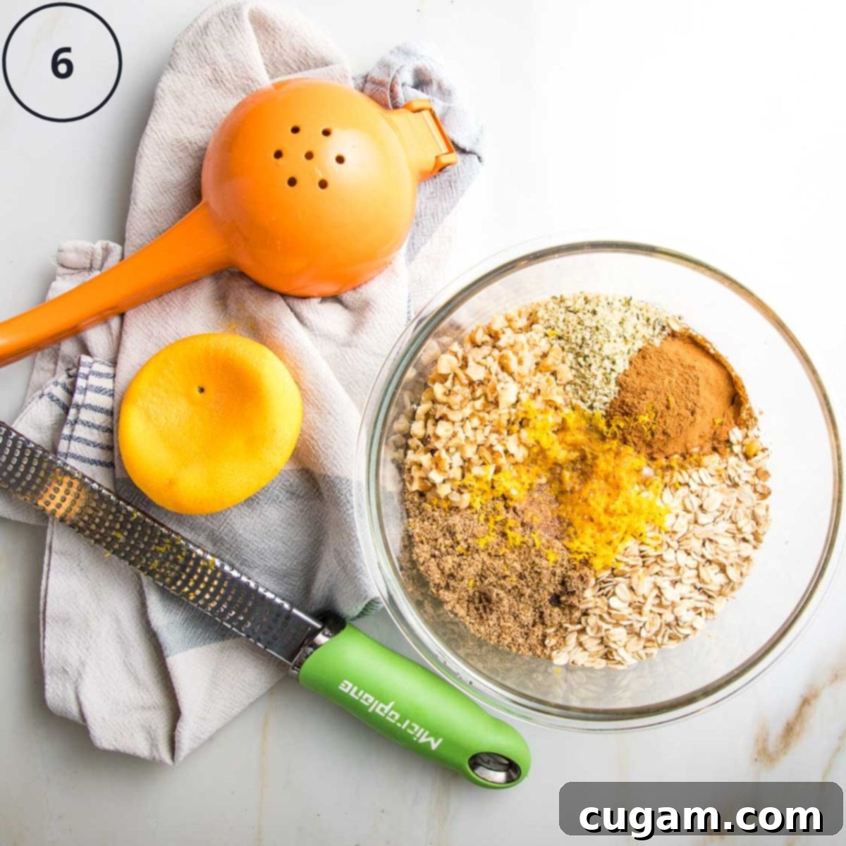 Orange, zested and juiced into a bowl with oats, nuts, flax, cinnamon and hemp seeds.