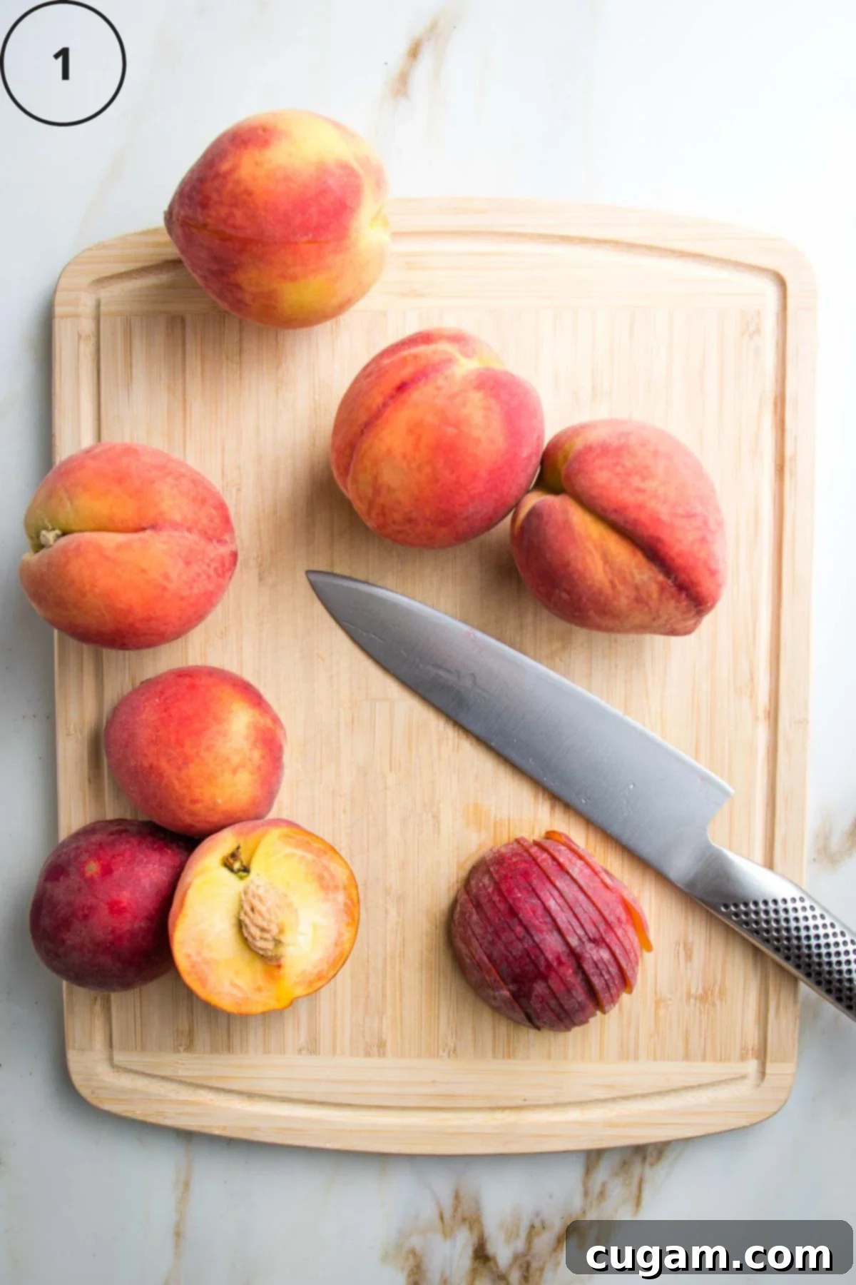 Cutting board with fresh whole peaches, one cut in half and then into slices for demonstration.