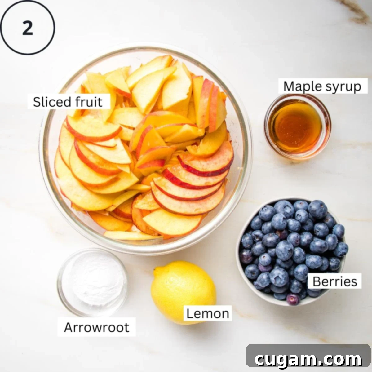 Sliced peaches in a bowl with arrowroot, lemon, blueberries and maple syrup in small dishes all labeled.