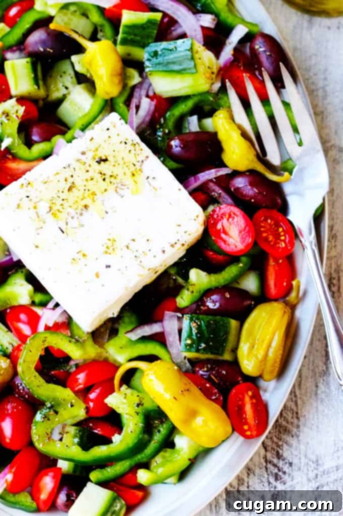 Horiatiki Salad (Greek Village Salad) served on a plate with fresh vegetables and a block of feta.