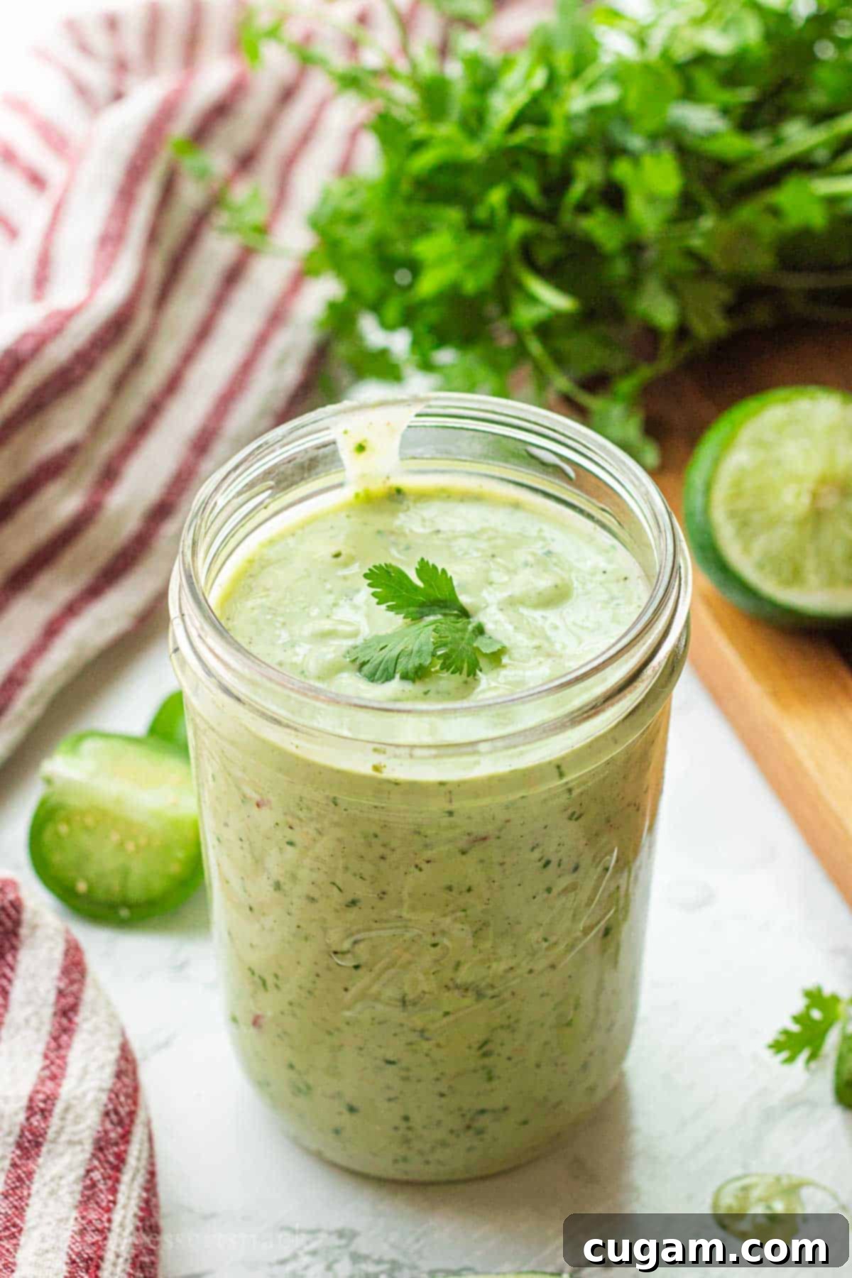 A mason jar filled with bright green avocado lime ranch dressing, sitting on a pristine marble surface, ready to be enjoyed or stored.