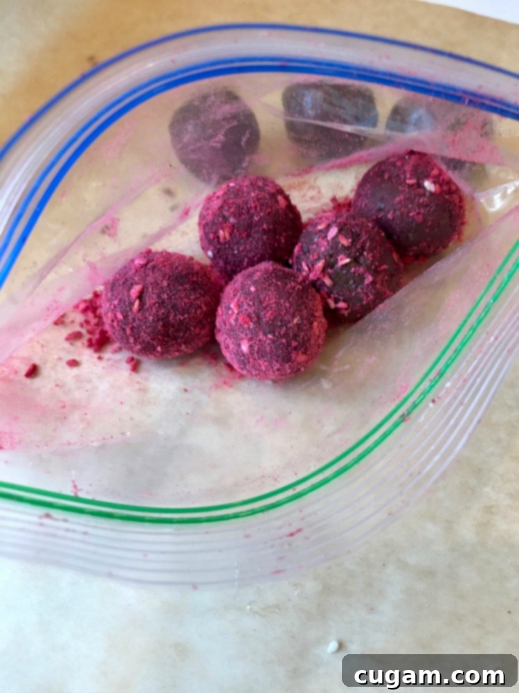 Ziploc baggie with a few chocolate bliss balls that are coated in a redish pink powder. 