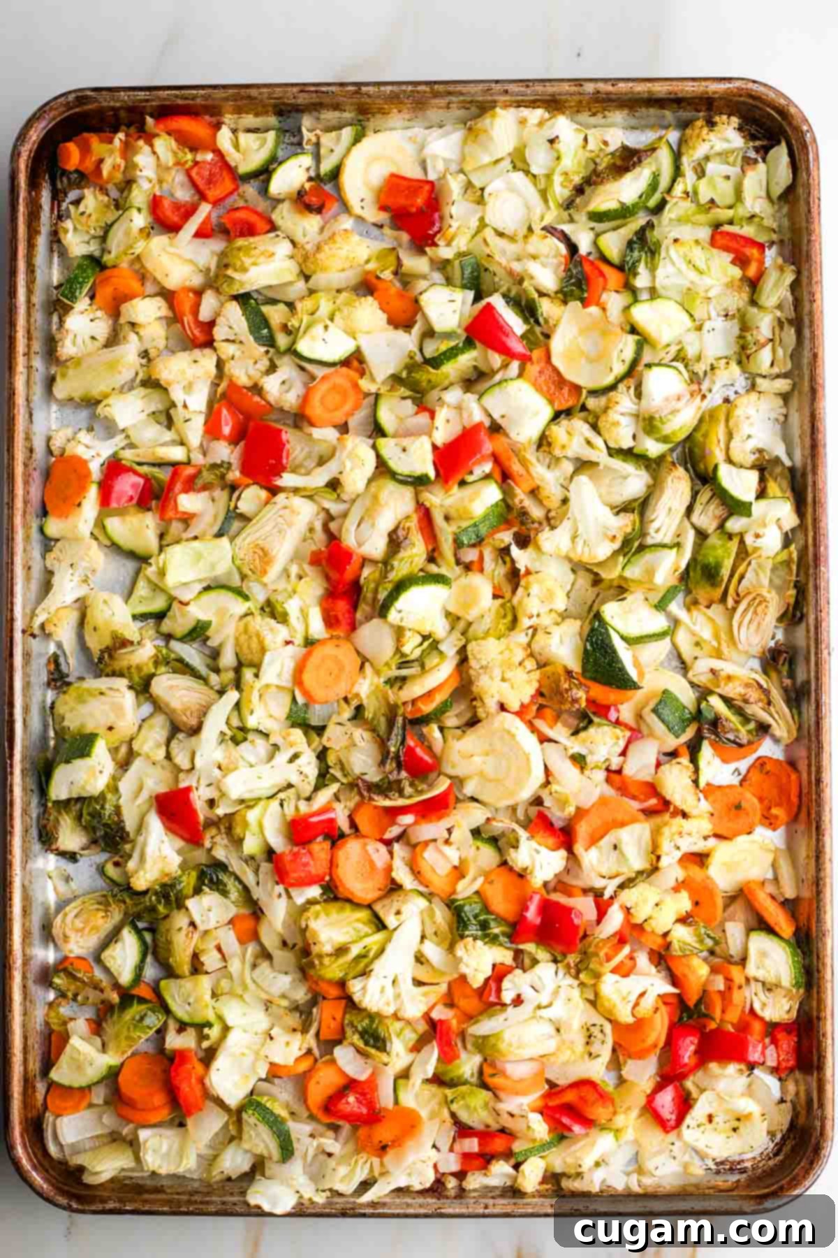 Sheet pan full of vibrant, perfectly roasted vegetables after the second stage of roasting.