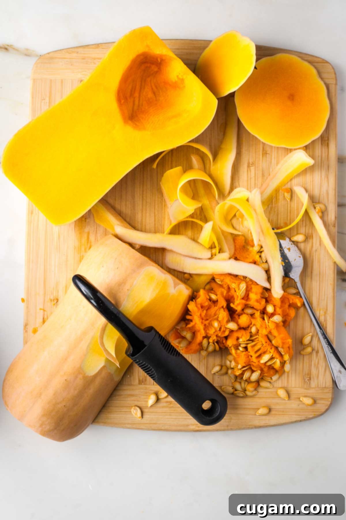 Butternut squash, halved, seeds scooped out, vegetable peeler removing skin.