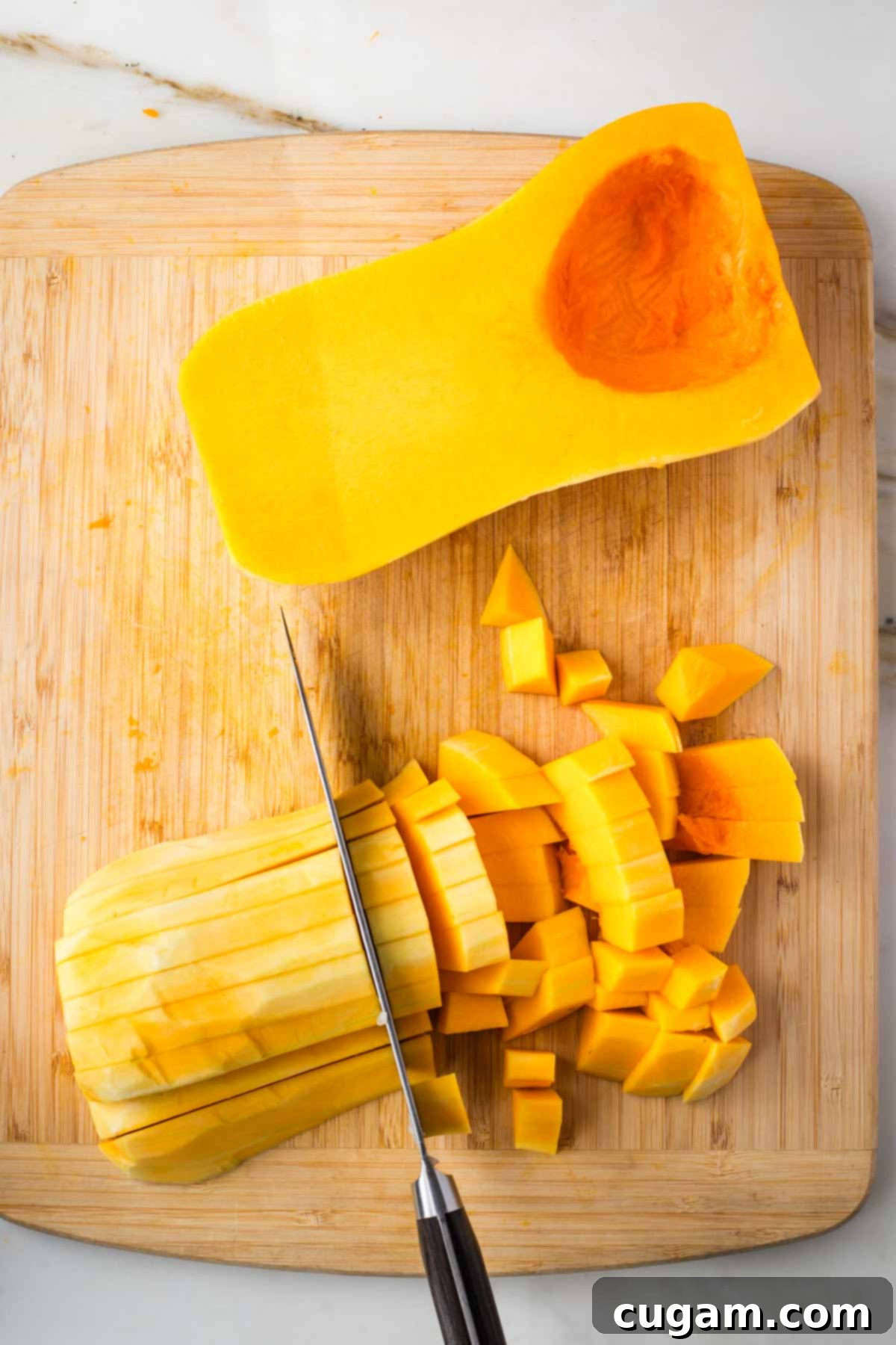Cutting peeled butternut squash into small dice.